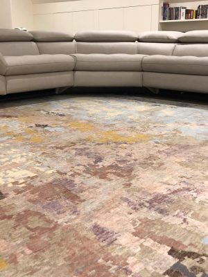 multi-coloured pastel abstract rug with grey corner sofa
