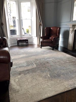 grey abstract rug with wool and silk and leather armchair