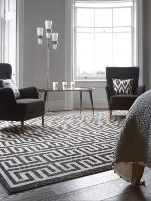 geometric monochrome rug with greek key design in room with black armchairs